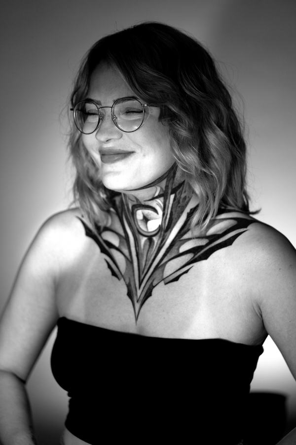 Ornamentales Tattoo an Hals und Brust in Schwarz und Grau